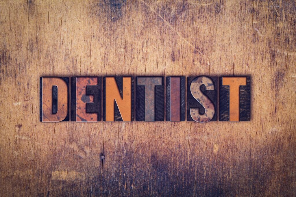 Dentist written on aged wooden background