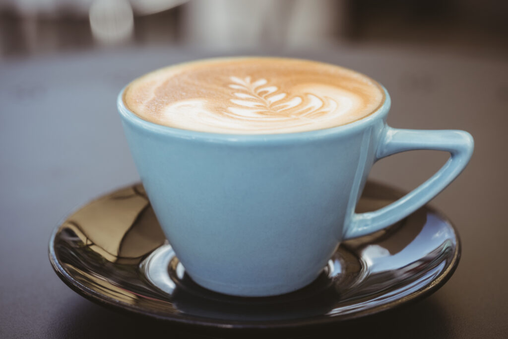 Cup of cappuccino with coffee art on wooden table