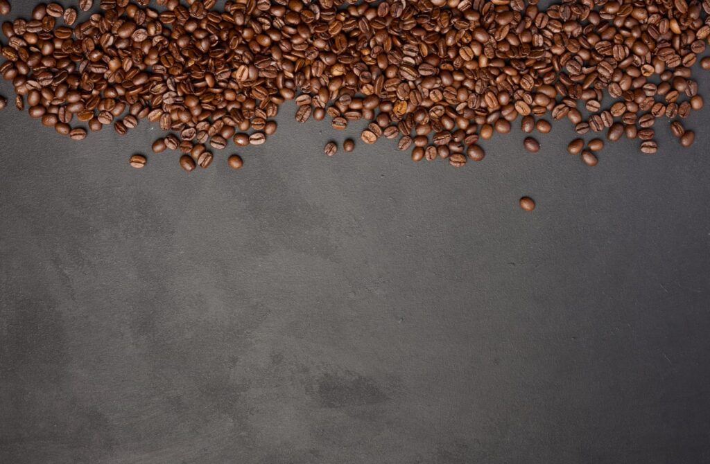 Scattered roasted coffee beans on black background top view
